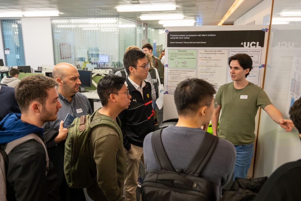 A student presents his poster to a crowd of interested listeners