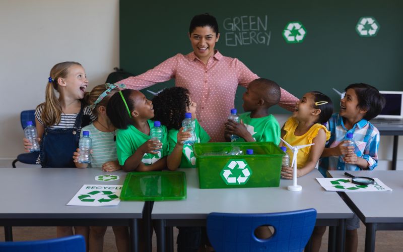 Happy schoolchildren learn about green energy with their teacher in a classroom.