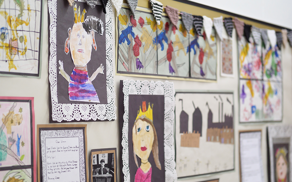Primary school children's writing and drawings about the Victorians pinned to a classroom wall. 