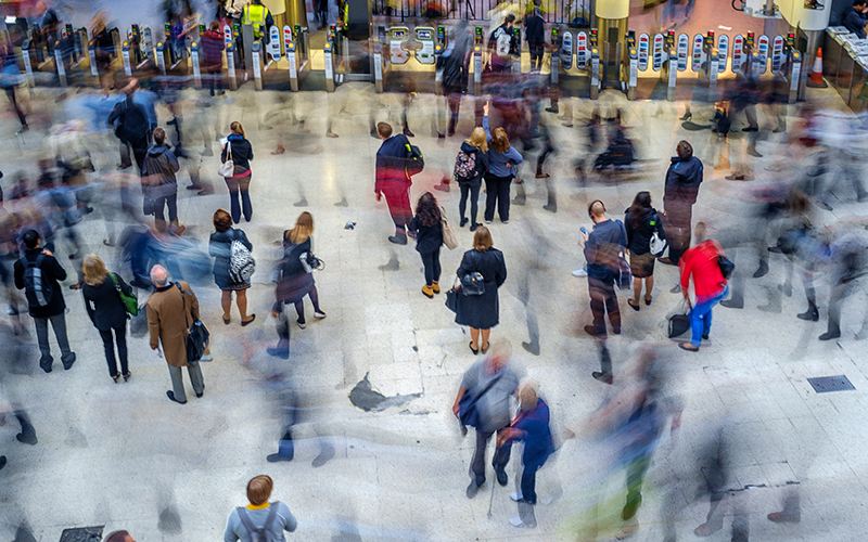 Commuters walk around a London station. Some are blurry with movement. Image credit: Chris Mann via Adobe Stock.