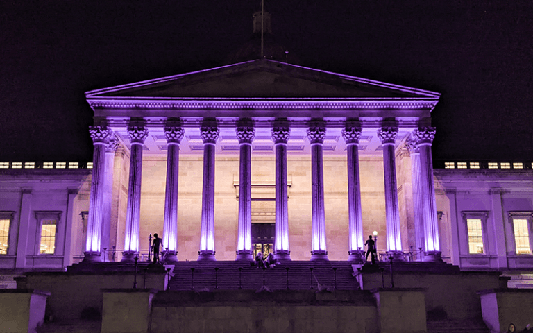 The stone columns of the UCL Wilkins building lit in purple to mark Holocaust Memorial Day.