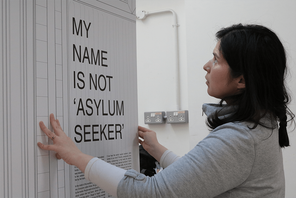 A black-haired woman assembling a board featuring the exhibition title.