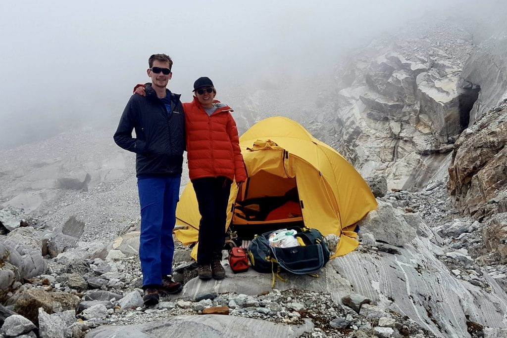A doctor and nurse standing on a mountain, with a medic-tent in the background.