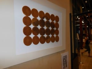artwork on wall consisting of nails hammered into symmetrical discs of waffle