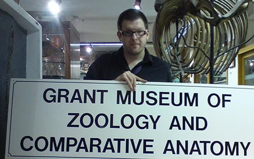 Mark Carnall, Curator of the Grant MUseum of Zoology holding the old museum sign