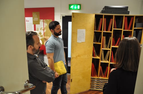 Language specialists looking into an open cupboard filled with papyri