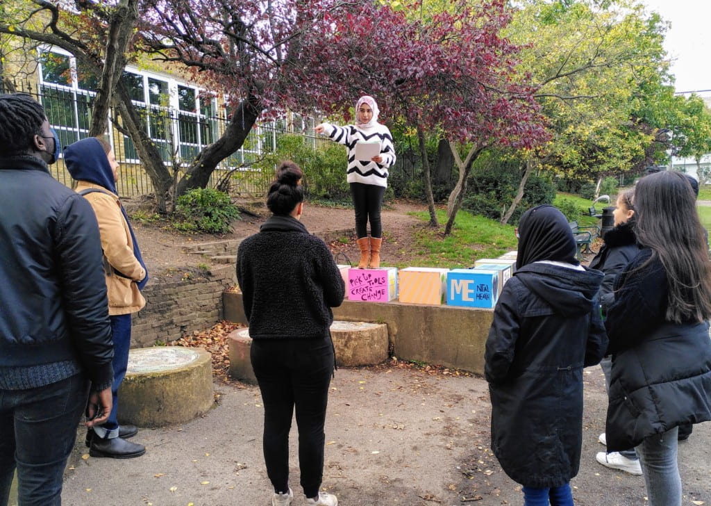 Young people at speakers corner with soapboxes they have decorated, giving speeches on social issues