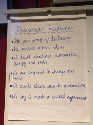 An image showing a poster with Discussion Guidelines handwritten on it. The guidelines are that we give proof of listening, we respect each other's ideas, we build, challenge, summarise, clarify and probe, we are prepared to change our mind, we invite others into the discussion and we try to reach a shared agreement. 