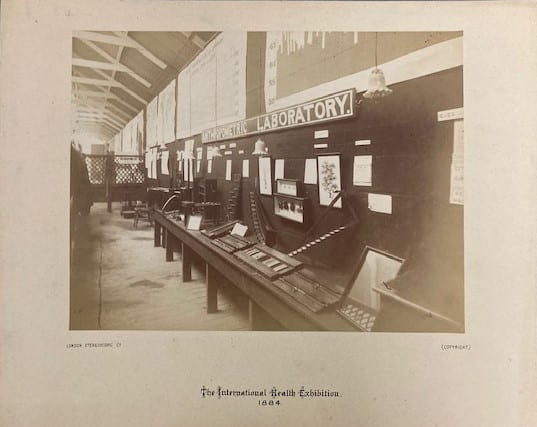 Sepia photograph of the Anthropometric Laboratory, South Kensington, 1884. Wood cases stretch into the distance. 