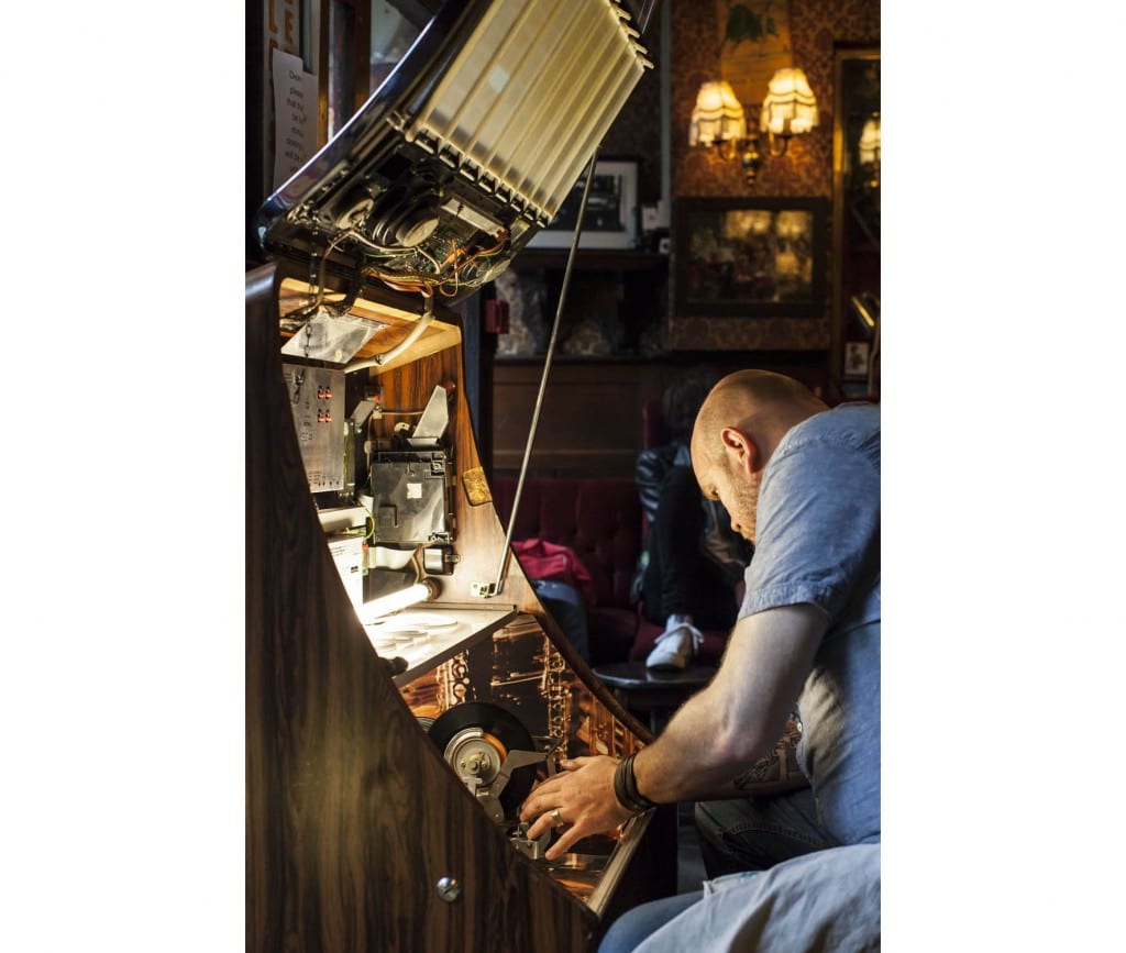 Bradley's Spanish Bar in 2014; fixing the jukebox (© Historic England, Chris Redgrave)