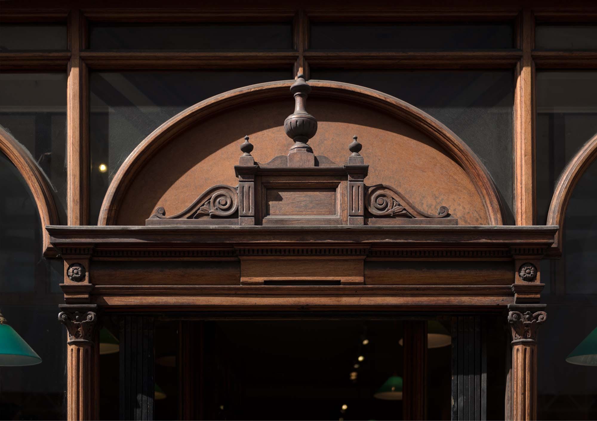 Pediment over the entrance to Daunt Books, 83 Marylebone High Street. Photographed by Chris Redgrave © Historic England.