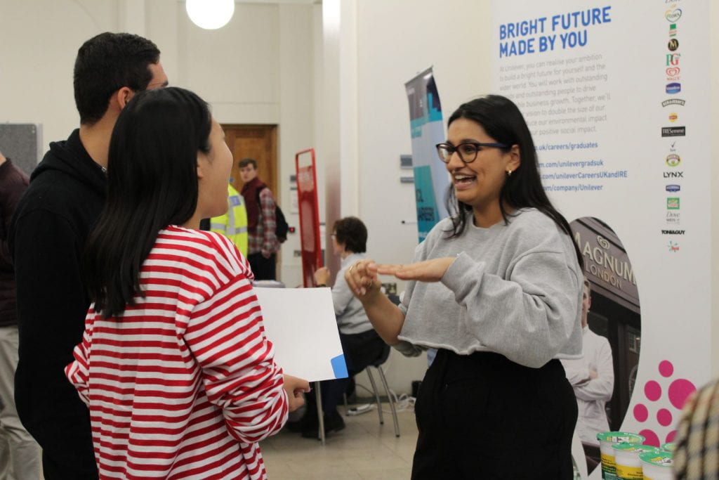 Two student talking to an employer at a careers fair